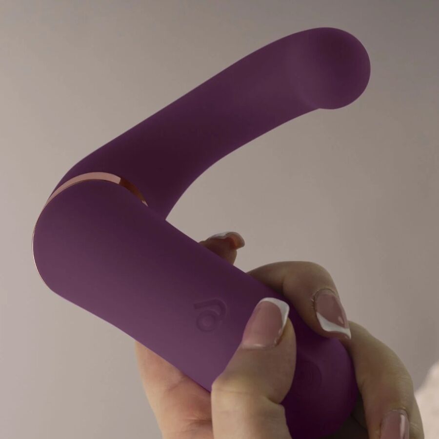 Lila Vibrator in Hand gehalten. Goldfarbener Akzent. Glatte Oberfläche.