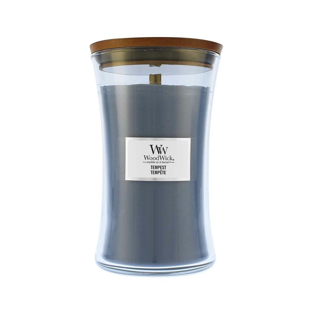 Graue Kerze im Glasbehälter mit Holzdeckel. Etikett mit "WoodWick Tempest".