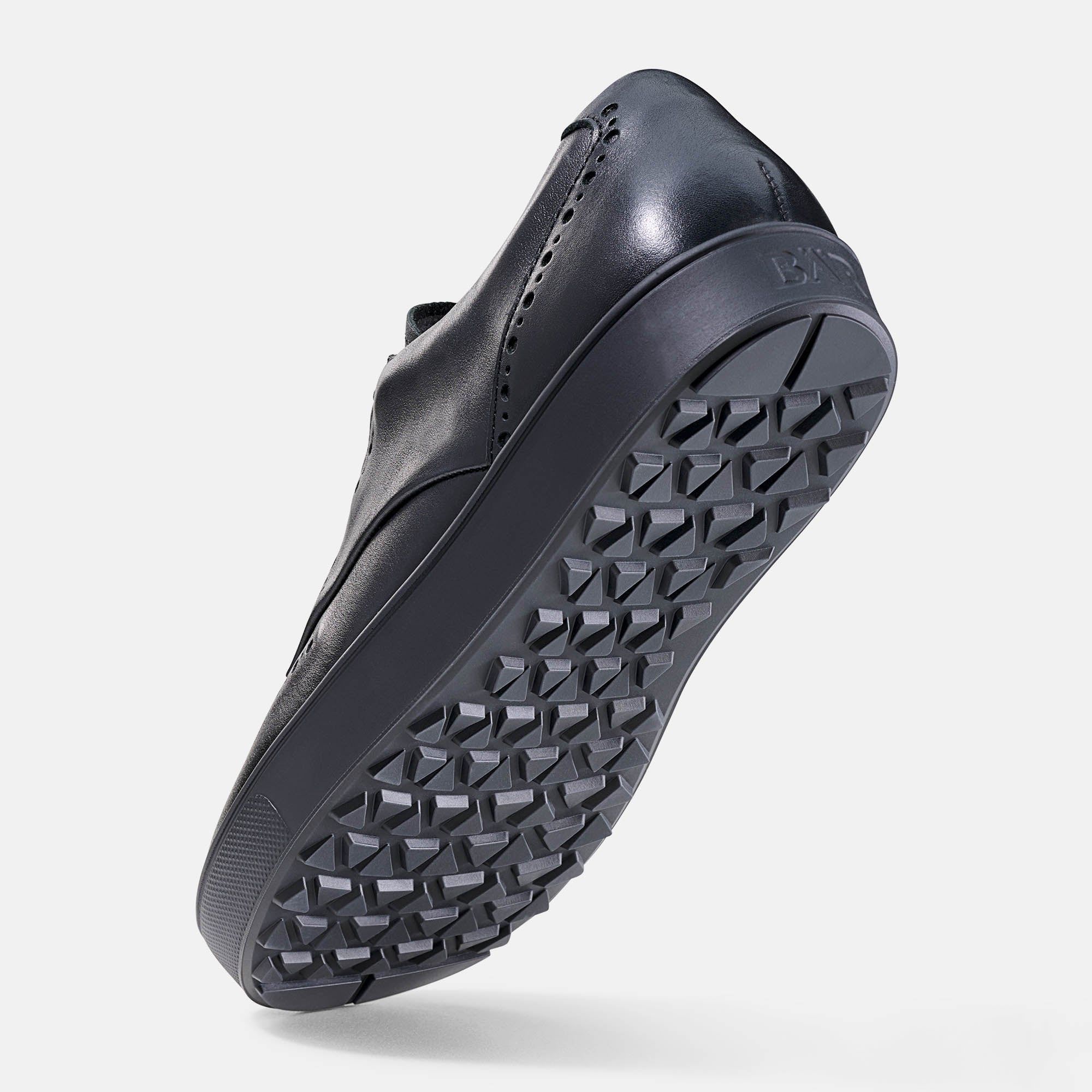 Schwarzer Herrenschuh, Unterseite. Profilierte Sohle. Schuh schräg von unten.