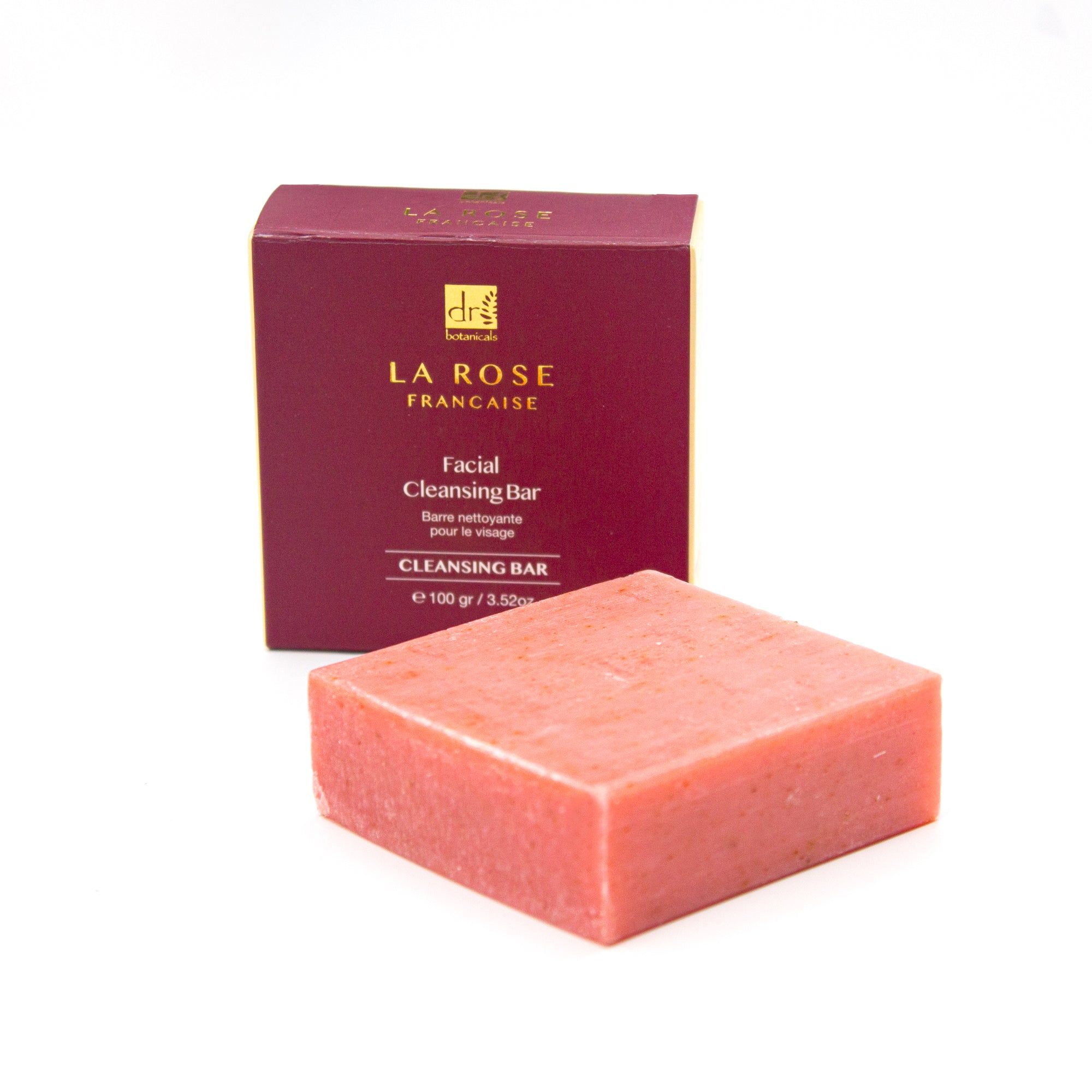 Rosa Blockseife neben Verpackung. Verpackung mit Logo und Text. "Facial Cleansing Bar".