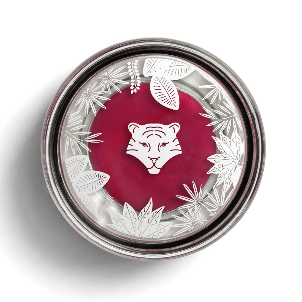 Runder Behälter mit rotem Inhalt, silbernem Rand und Deckel mit Tigerkopf-Motiv und Blättern. Top-Ansicht.