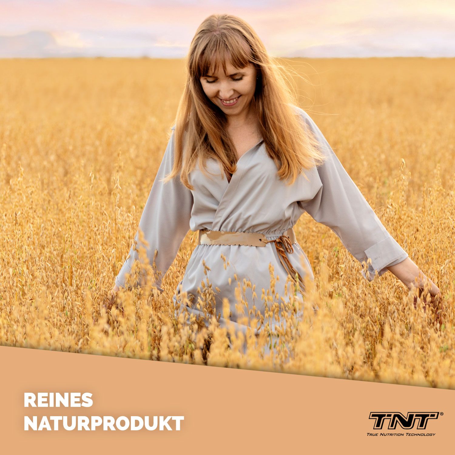 Frau im Feld stehend. Sie trägt ein graues Kleid. Aufschrift: Reines Naturprodukt. Logo: TNT.