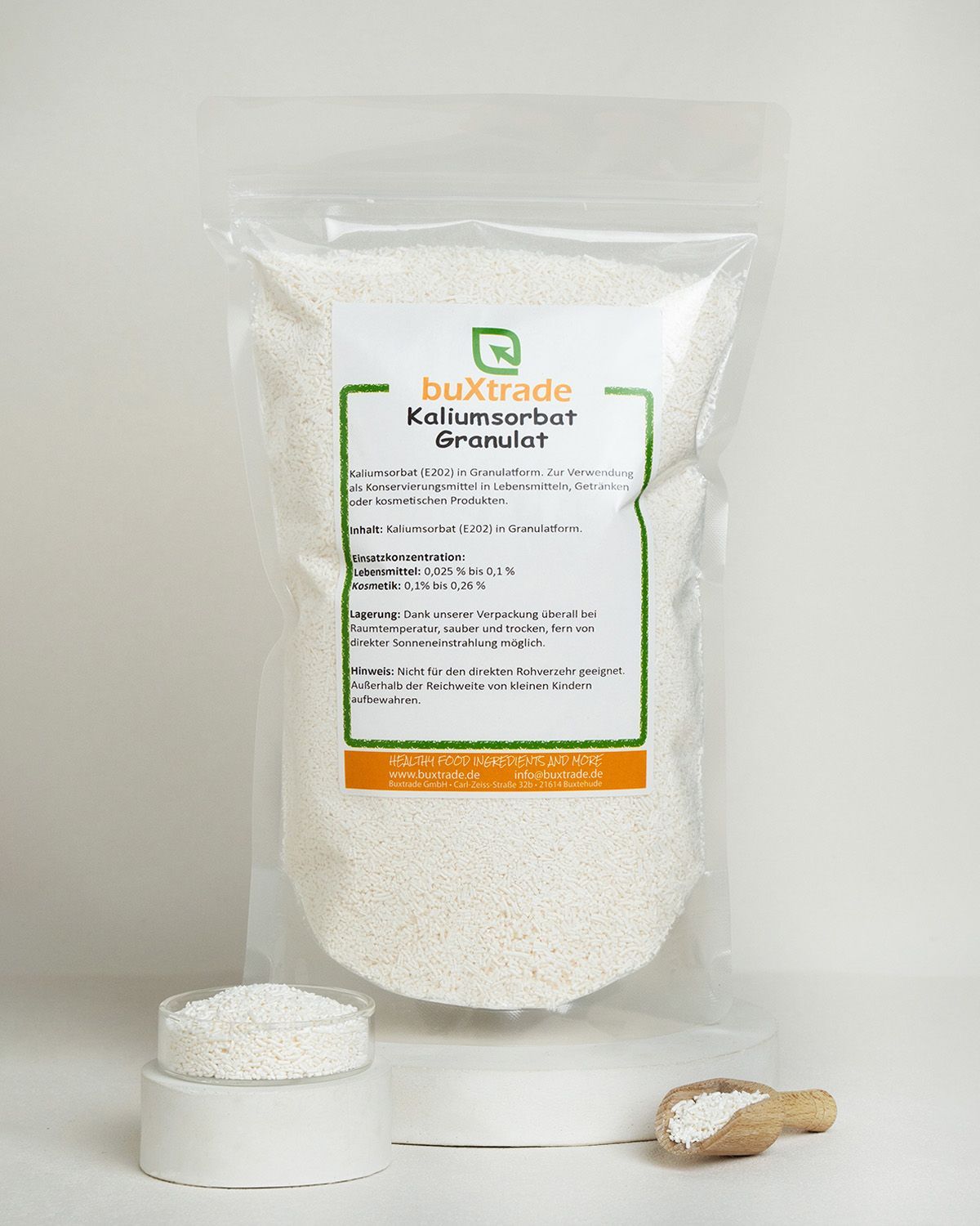 Verpackung mit buXtrade Kaliumsorbat Granulat, daneben ein kleines Gefäß und eine Holzschaufel mit Granulat.