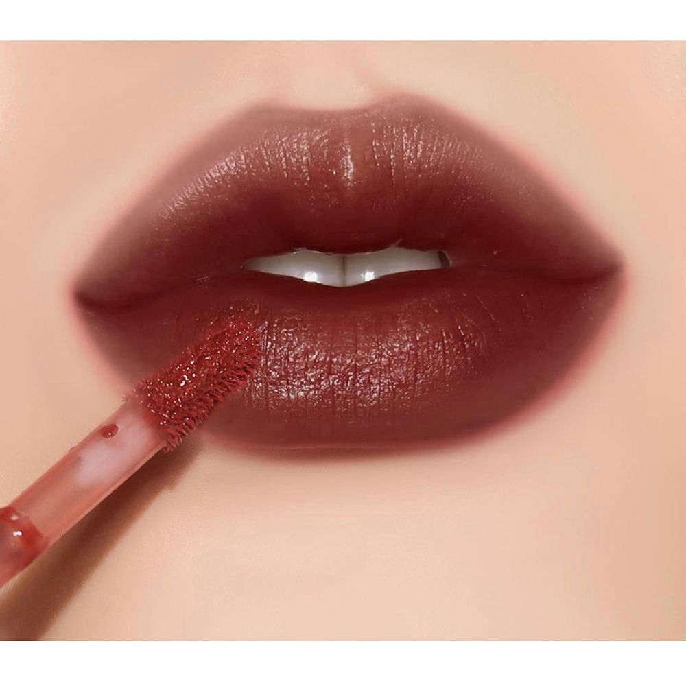 Nahaufnahme von Lippen mit aufgetragenem braunem Lipgloss. Applikator sichtbar.
