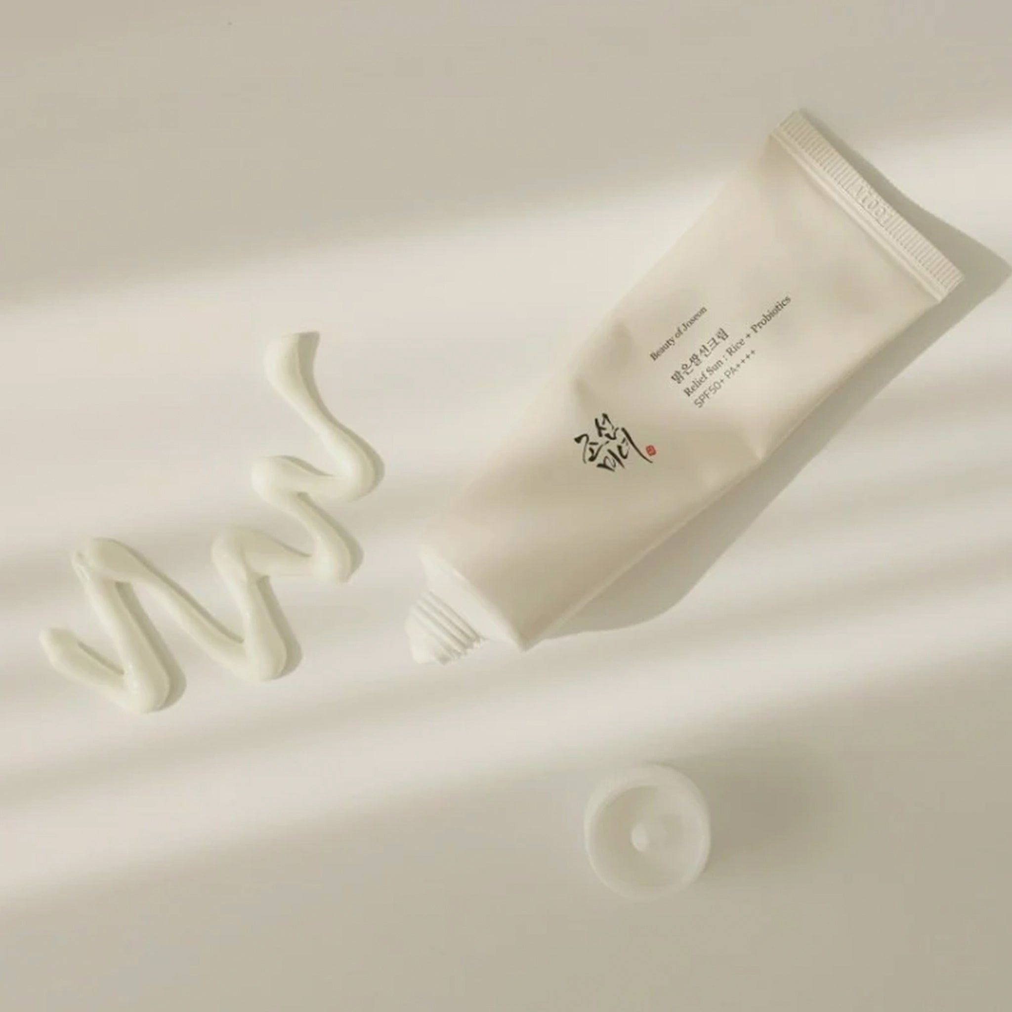 Eine Tube mit Creme und ein Klecks Creme daneben. Auf der Tube steht Text.