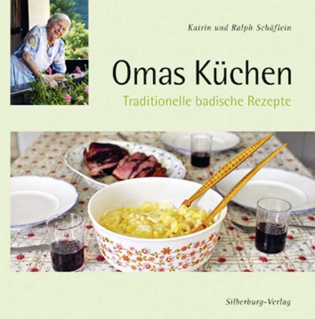 Buchcover mit Titel "Omas Küchen". Frau im Bild, Essen auf Tisch. Text: Traditionelle badische Rezepte. Verlag: Silberburg-Verlag.