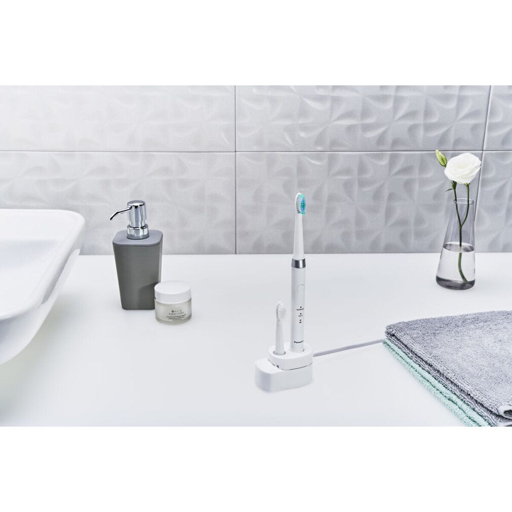 Elektrische Zahnbürste mit Ersatzbürste in Ladestation. Auf weißer Oberfläche. Weitere Badutensilien.