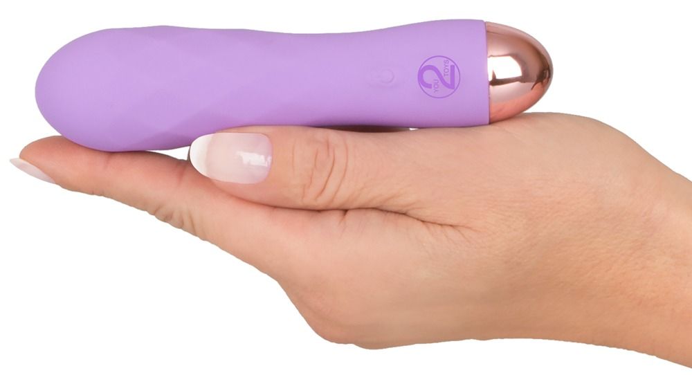 Lila Vibrator in einer Hand gehalten. Goldfarbene Spitze, Bedienknöpfe. Auf weißem Hintergrund.