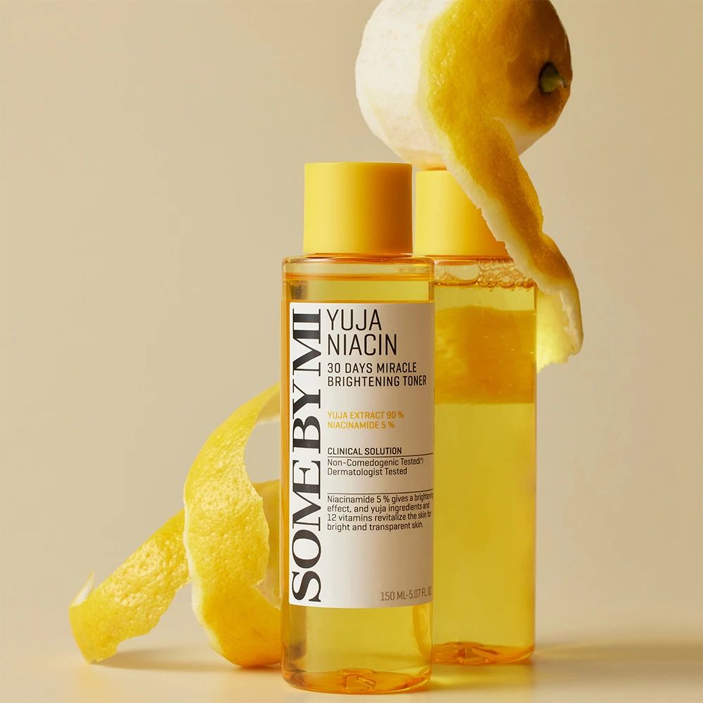 Zwei gelbe Flaschen mit weißem Etikett. Text: Yuja Niacin, 30 Days Miracle Brightening Toner. Zitronenschale daneben.