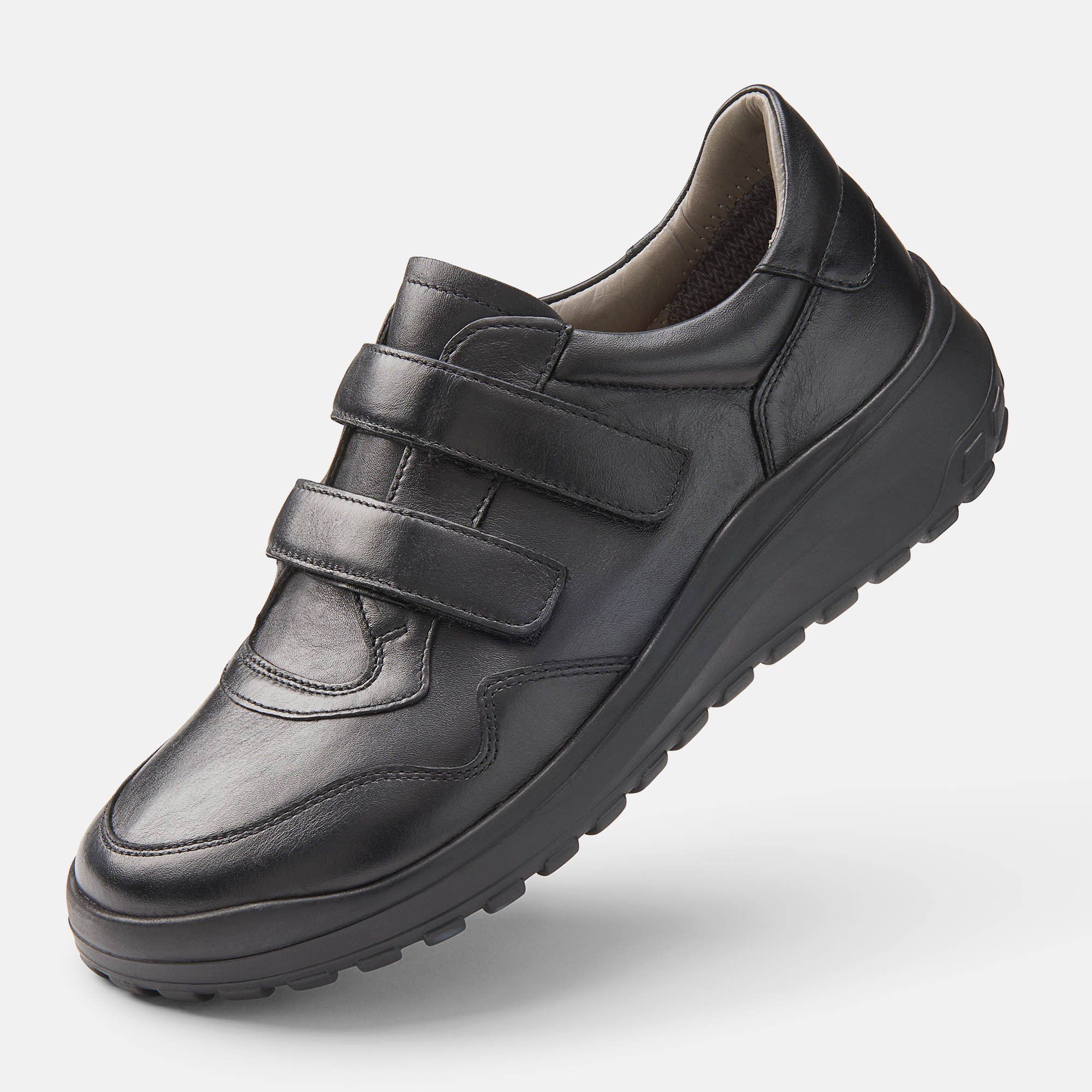 Schwarzer Herren-Slipper mit Klettverschluss. Breite Passform. Schuh von der Seite, leicht schräg gestellt.