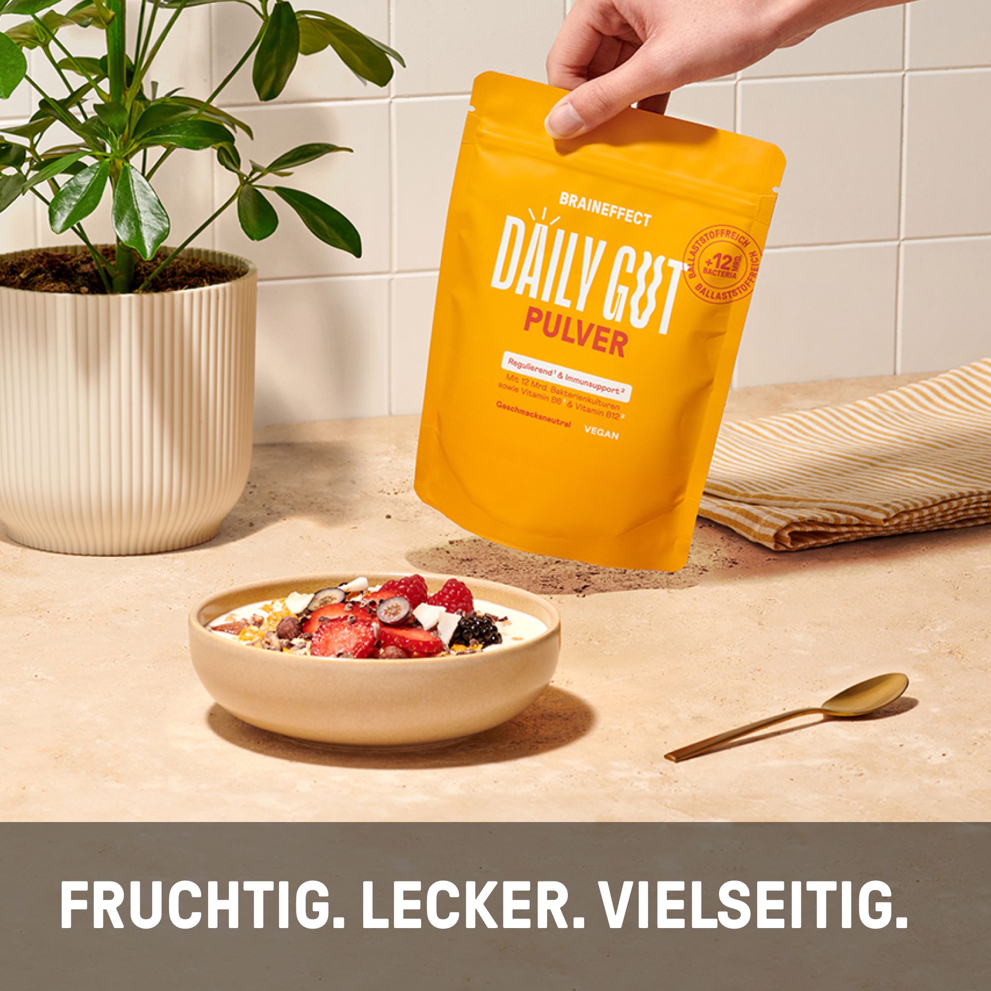 Schüssel mit Müsli und Früchten. Daneben eine gelbe BRAINEFFECT DAILY GUT PULVER Verpackung und ein Löffel.