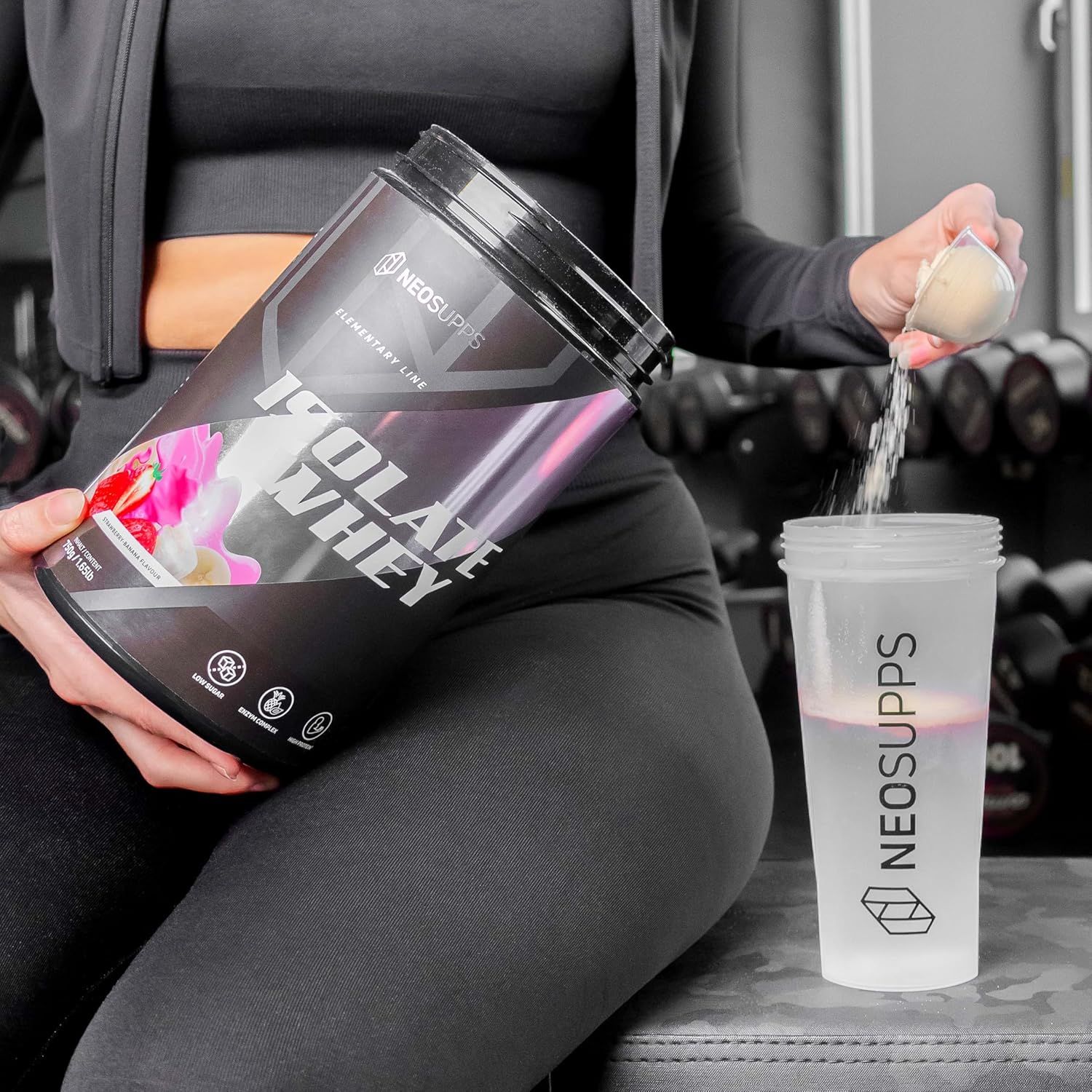 Person gießt Pulver aus Dose "ISOLATE WHEY" in Shaker. Aufschrift: NEOSUPPS. Erdbeer-Banane.