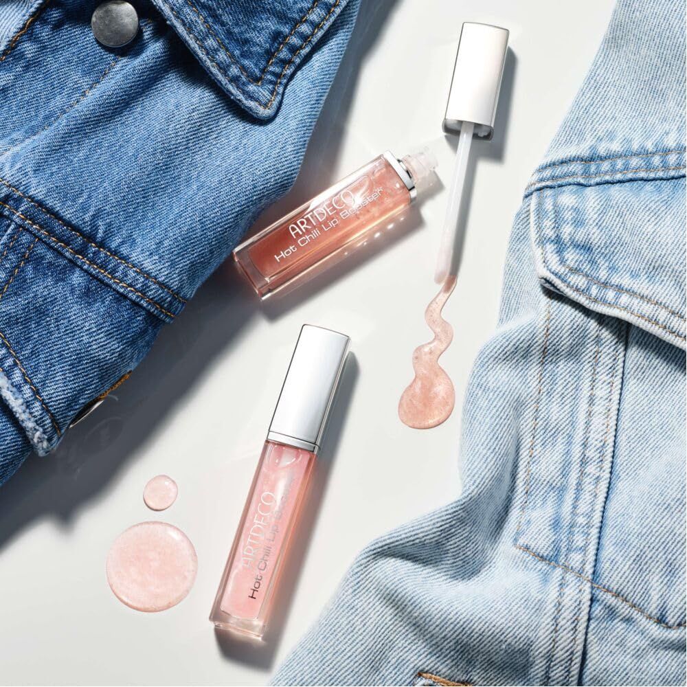 Drei Artdeco Hot Chili Lip Booster auf Jeansstoff. Ein Booster geöffnet, Produkt daneben. Produktbeschriftung sichtbar.