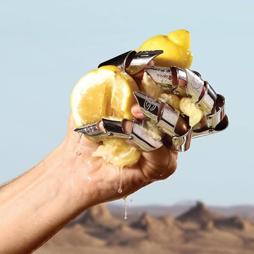 Hand mit silbernen Ringen presst Zitronen. Saft tropft. Blauer Hintergrund.