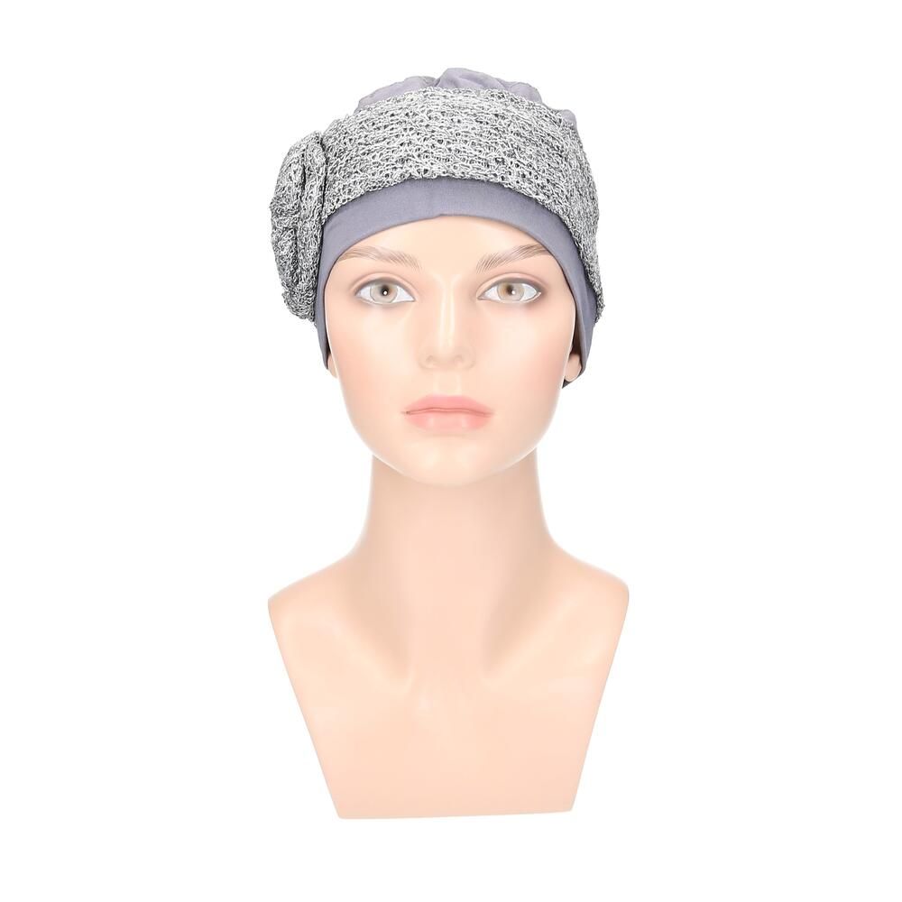 Grau/Silberfarbener Turban auf einer Büste. Der Turban hat eine verzierte Krempe und eine blütenförmige Applikation.