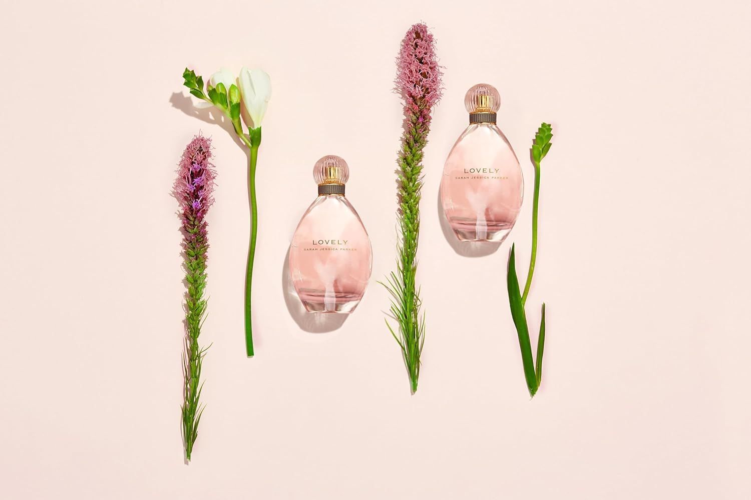 Drei Parfümflaschen mit Blumen. Birnenförmige Flaschen, umgeben von Blumen und Pflanzen auf rosa Hintergrund.