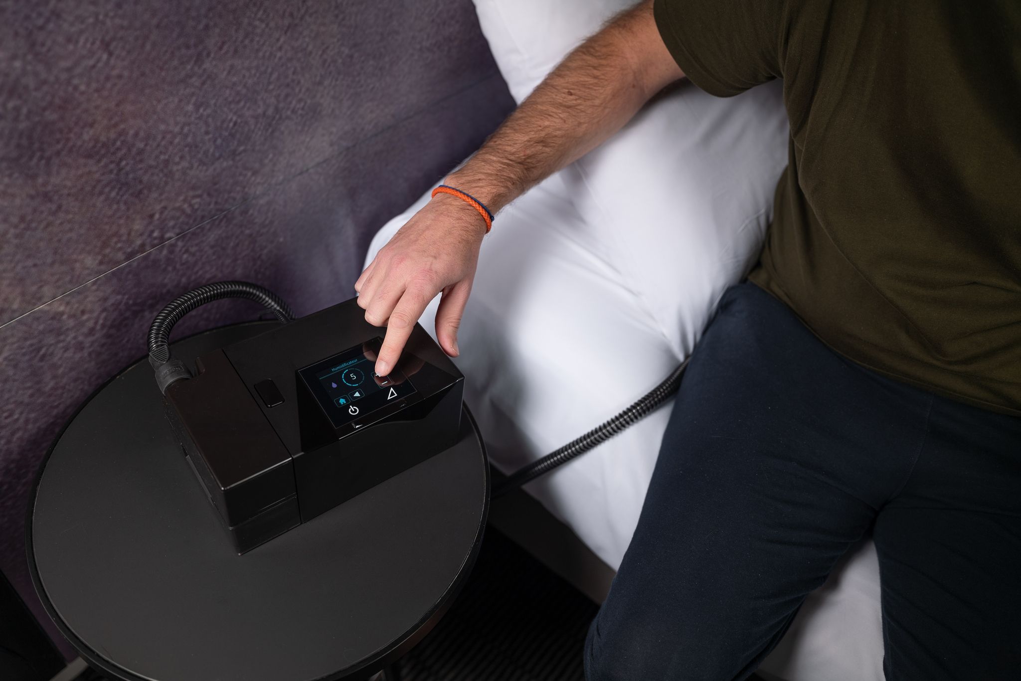 Person berührt das Display eines APAP-Geräts. Gerät steht auf einem Nachttisch.