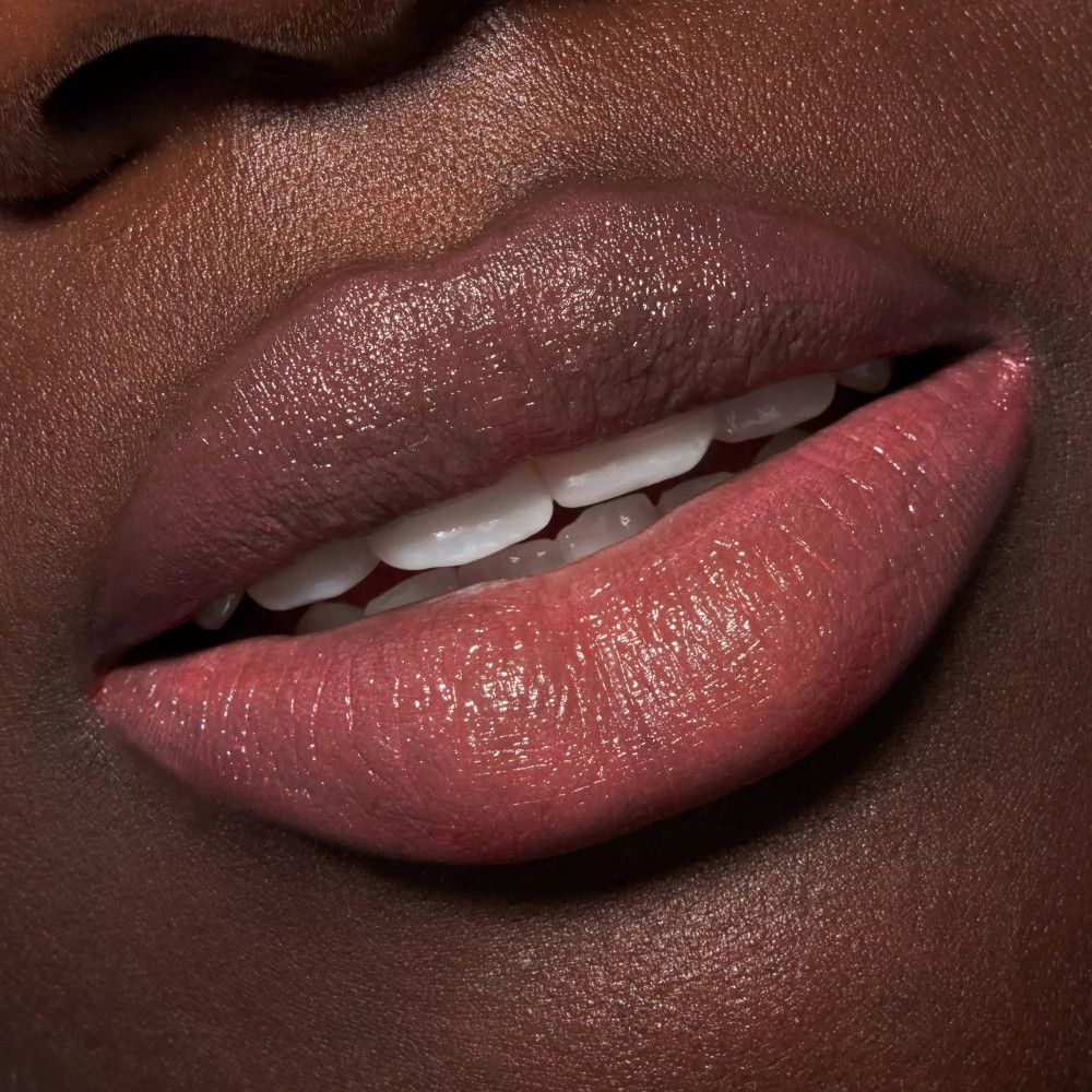 Nahaufnahme von Lippen, rosa Lippenstift. Dunkle Haut. Kosmetisches Produkt.