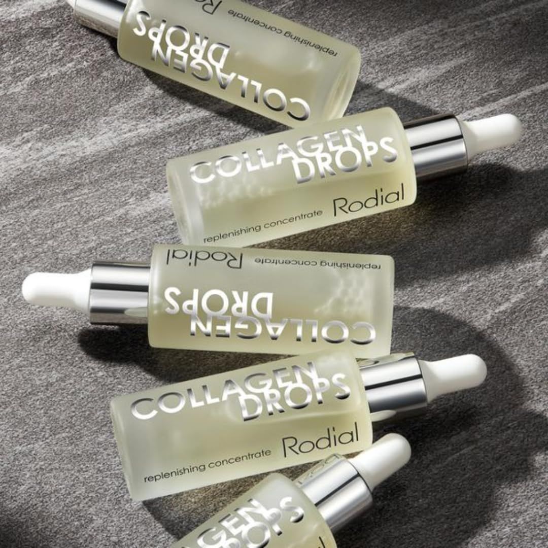 Mehrere Produktflaschen mit Pipetten. Text: Collagen Drops, Rodial. Auf grauem Untergrund.