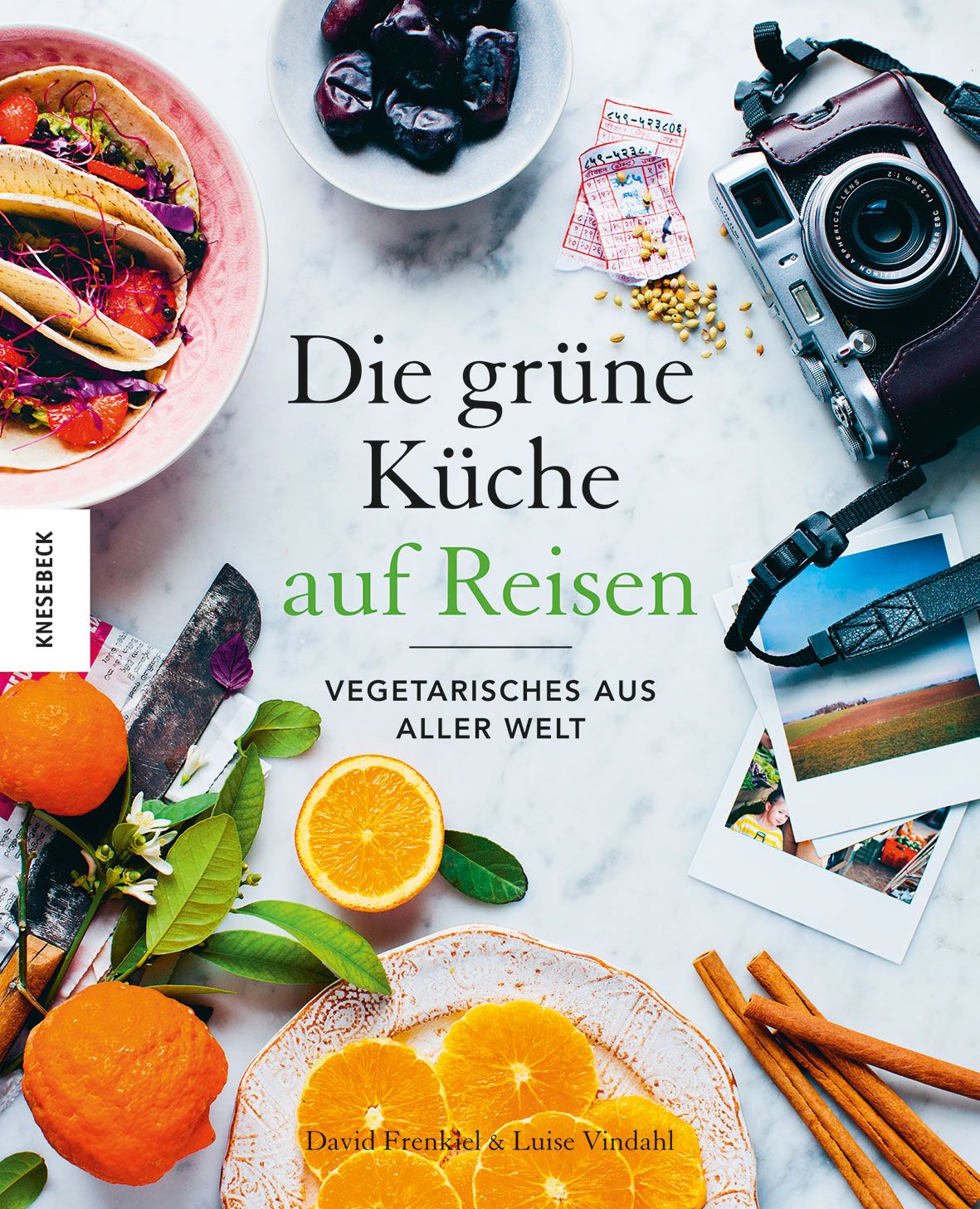 Buchcover: "Die grüne Küche auf Reisen". Titel und Untertitel in Großbuchstaben. Orangen, Essen, Kamera und Polaroid-Fotos.
