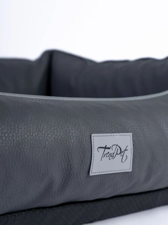 Graues Kunstlederbett mit Label 'TrendPet'. Label ist rechteckig mit schwarzer Schrift. Kunstleder hat eine strukturierte Oberfläche.