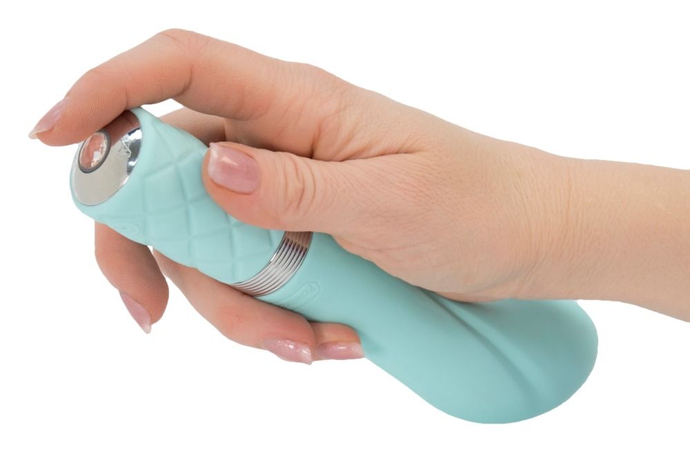 Hand hält teal-farbenen Vibrator. Zylindrischer Griff mit Rautenmuster, silberfarbener Ring, gebogener Kopf.