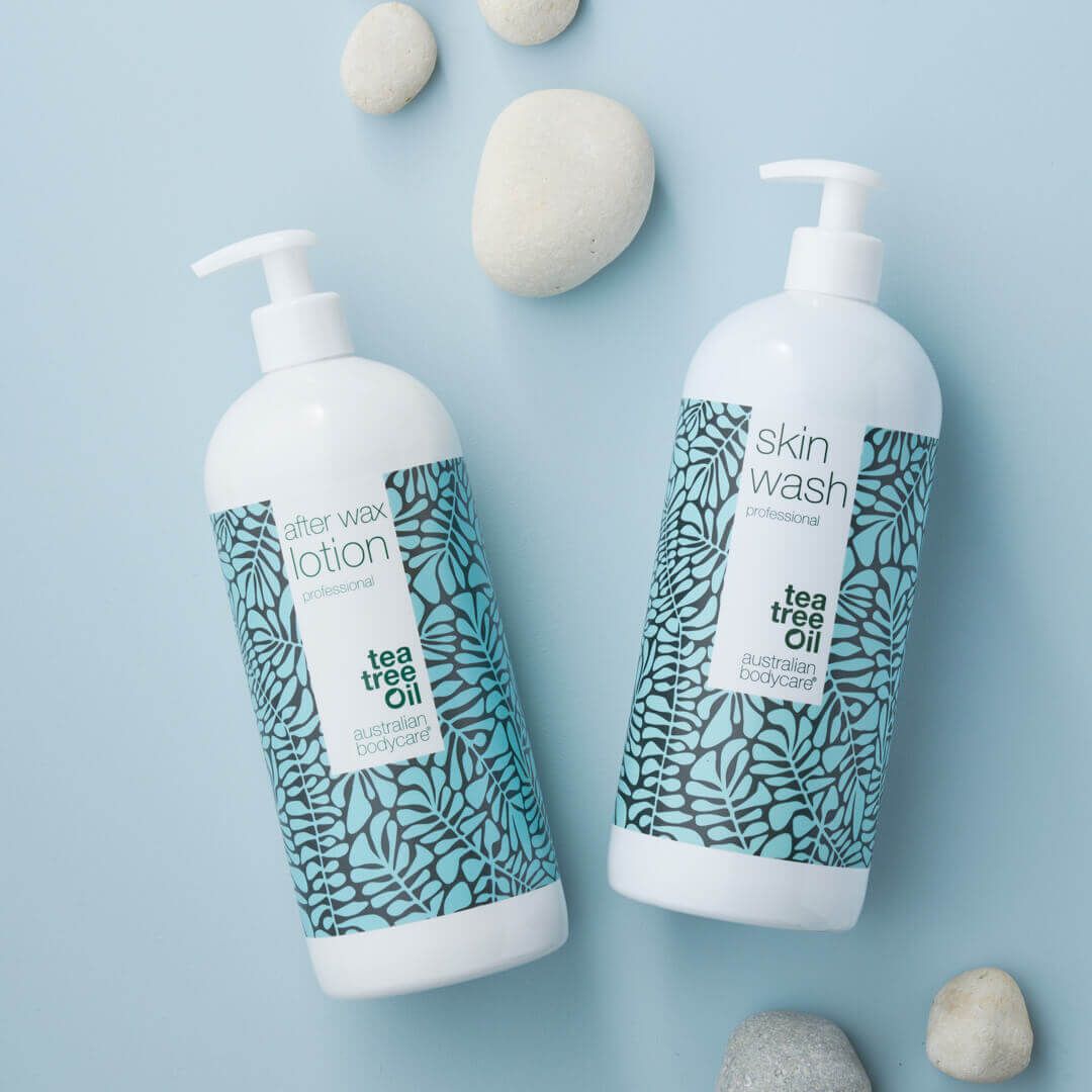 Twee flessen After Wax Lotion en Skin Wash. Witte flessen met bloemmotief en pomp. Op blauwe achtergrond.