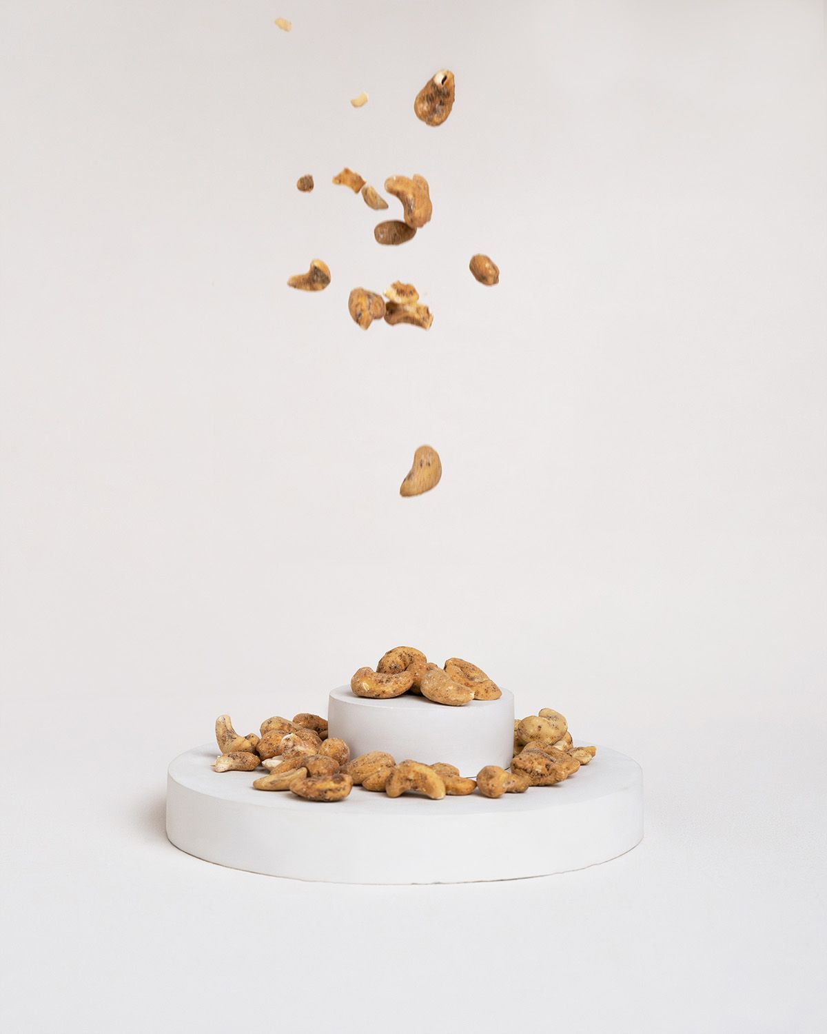 Cashewkerne fallen auf eine weiße Plattform. Einige Kerne liegen auf einer erhöhten, runden Fläche.
