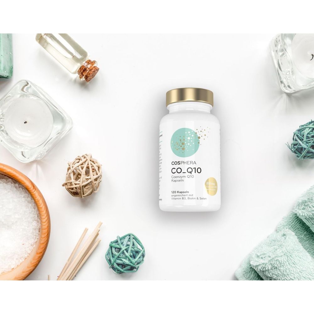 Weiße Flasche Cosphera Coenzym Q10 Kapseln, umgeben von Wellness-Dekorationen. Aufschrift: CO_Q10, 120 Kapseln, angereichert mit Vitamin B3, Biotin & Selen.