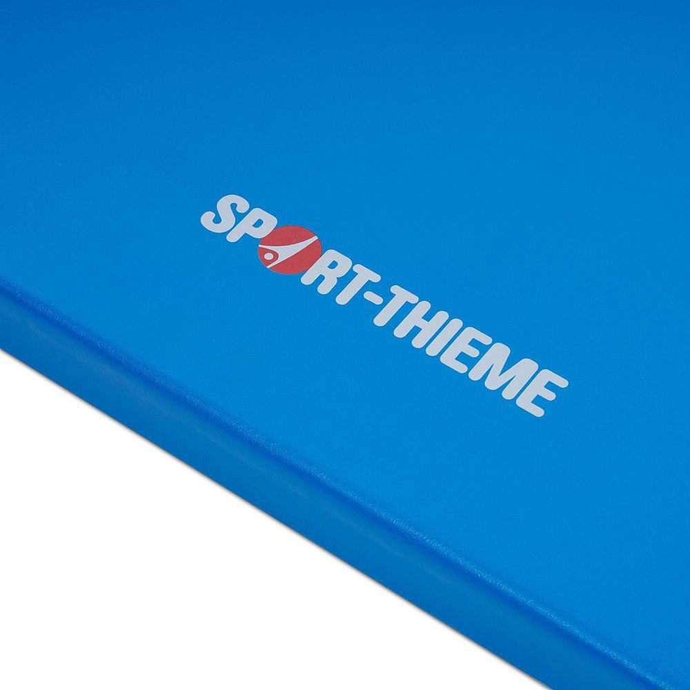 Blaue Turnmatte mit weißem Schriftzug Sport-Thieme. Rotes Herz-Symbol im Schriftzug.