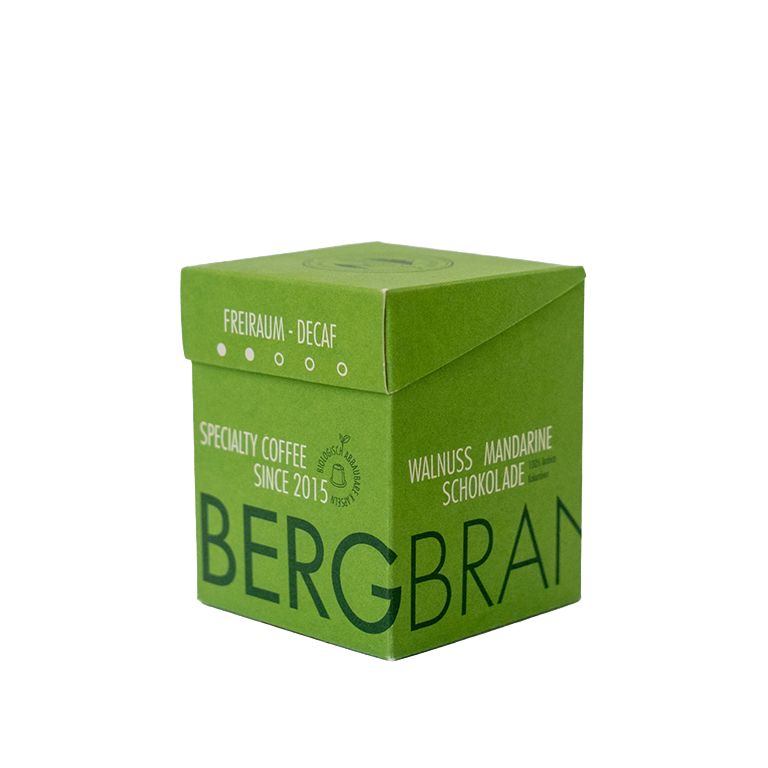 Grüne Verpackung mit BERGBRAND-Logo. Text: Freiraum-Decaf, Specialty Coffee, Walnuss Mandarine Schokolade.