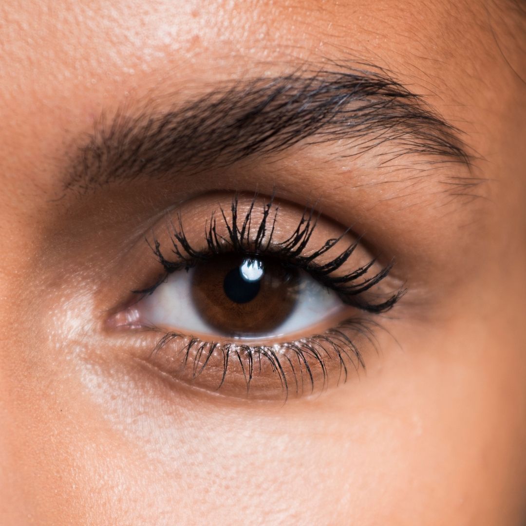 Nahaufnahme eines Auges. Braune Iris, dunkle Wimpern, dunkle Augenbraue. Hautton.