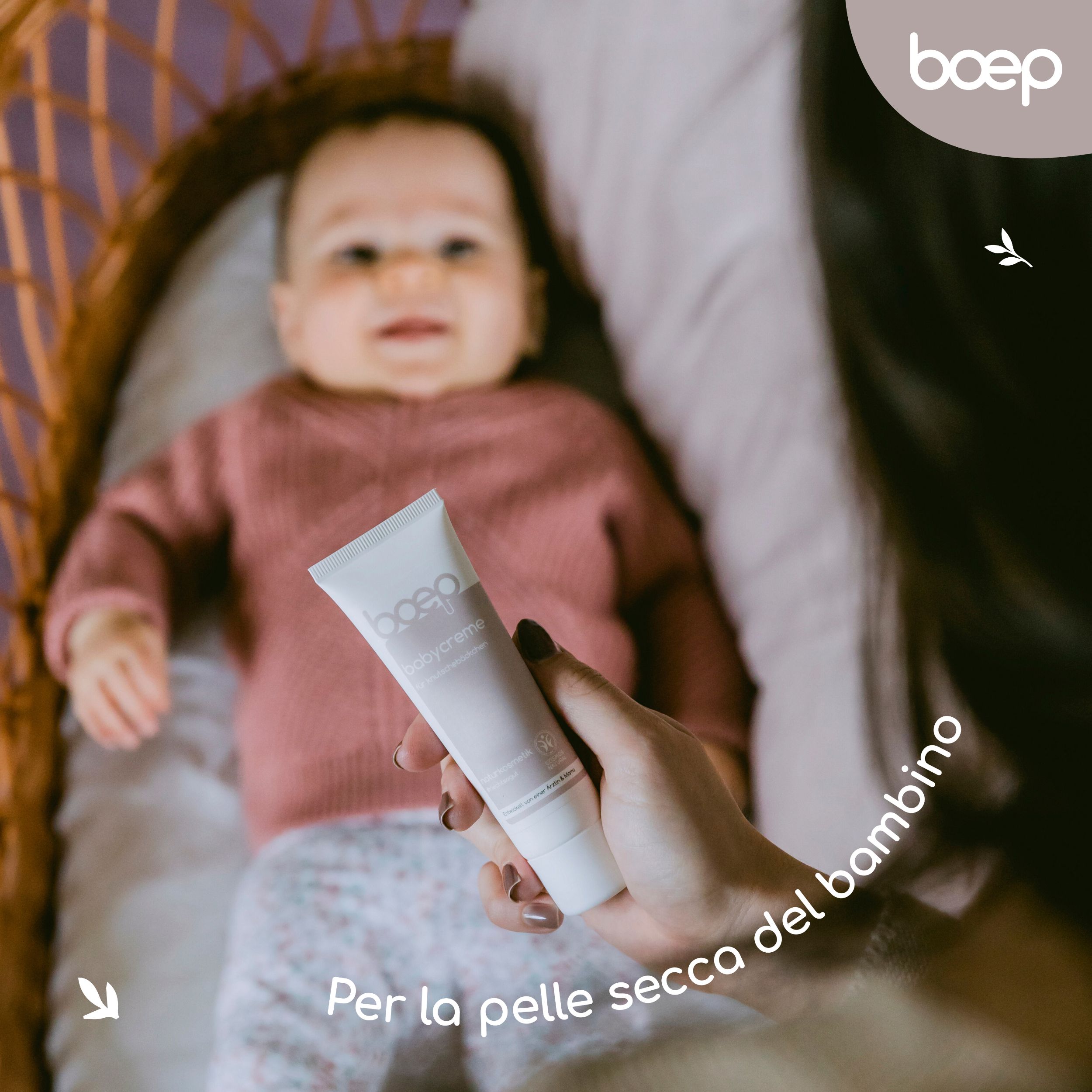 Baby im Bettchen. Hand hält Tube. Text: "Per la pelle secca del bambino".