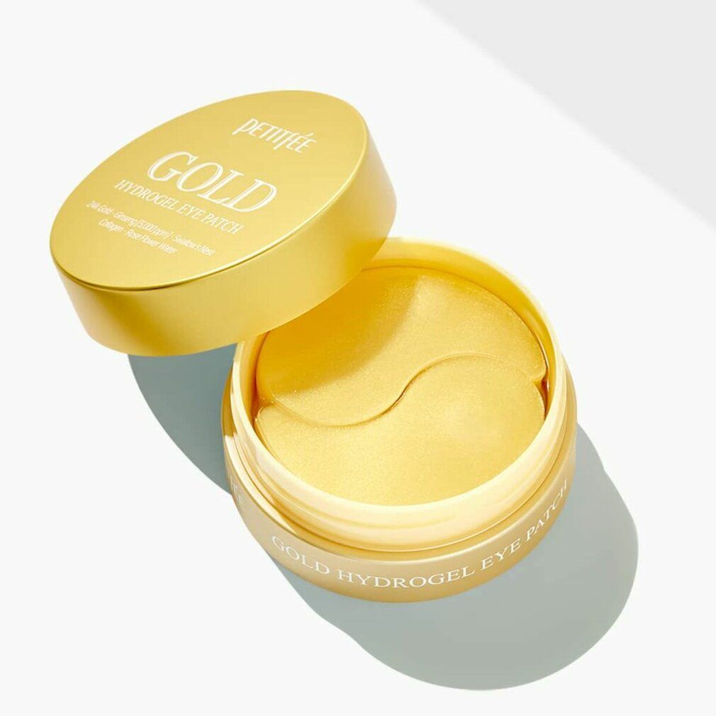Goldfarbene Augenpads in einem goldenen Behälter. Deckel mit "GOLD HYDROGEL EYE PATCH"-Schriftzug. Offener Behälter mit Pads.