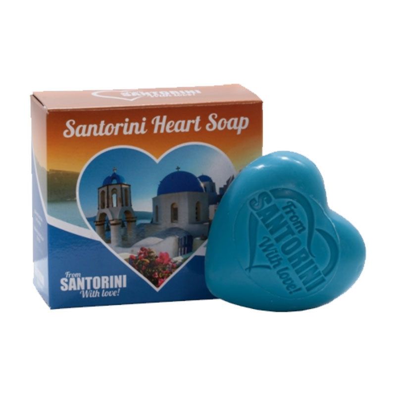 Blaues Herzseifenstück neben Verpackung. Aufschrift: Santorini Heart Soap. Verpackung mit Landschaftsbild.
