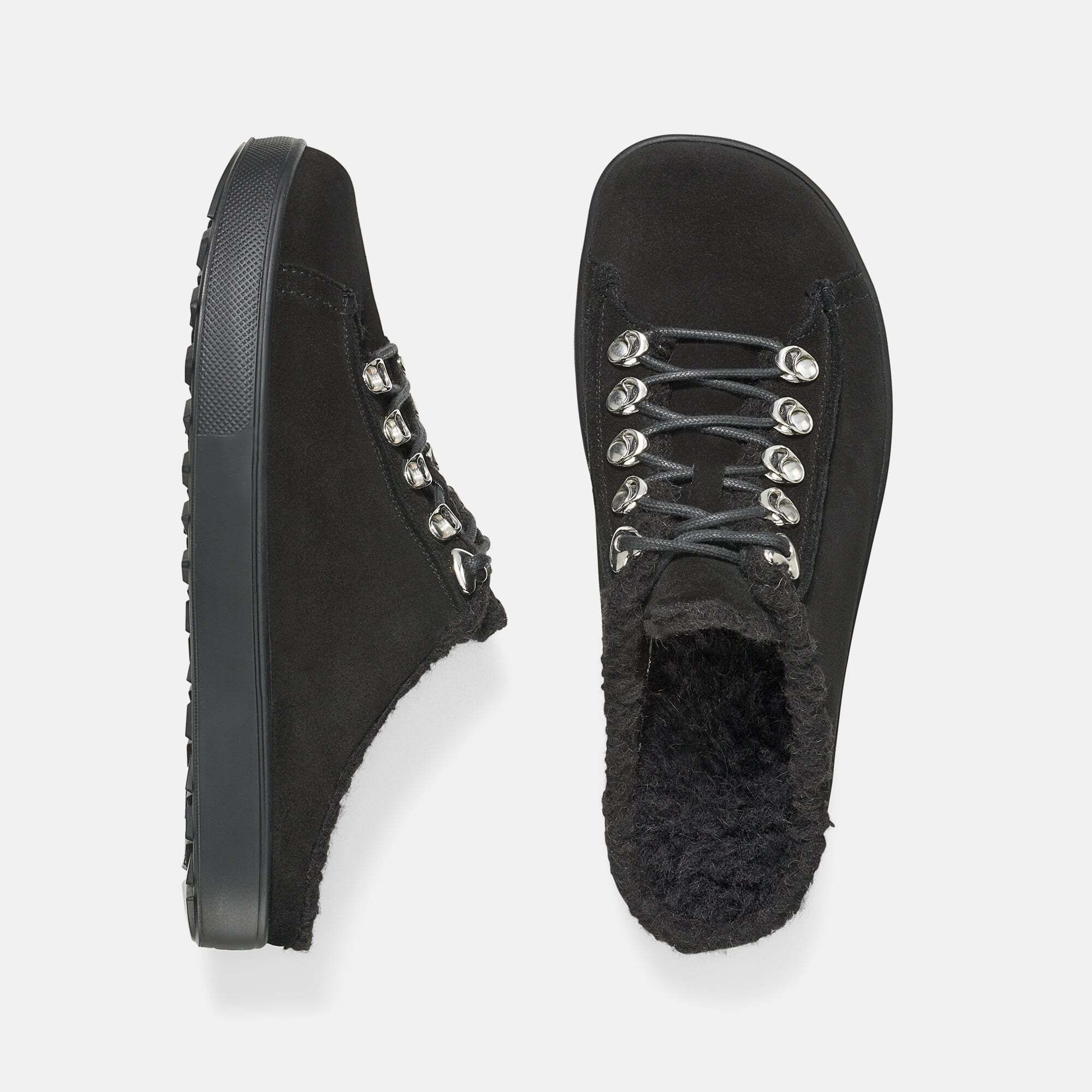 Draufsicht auf schwarze Pantoletten. Schnürung, Fellfutter, breite Passform. Sohle und Obermaterial aus Textil.