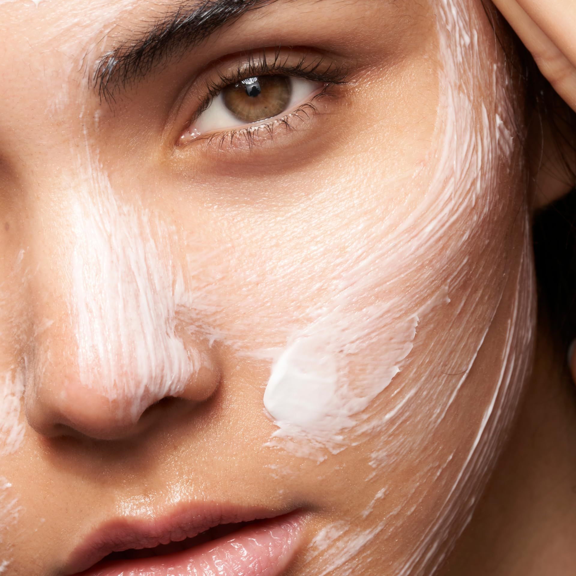 Nahaufnahme eines Gesichts mit weißer Creme. Creme auf der Haut sichtbar.