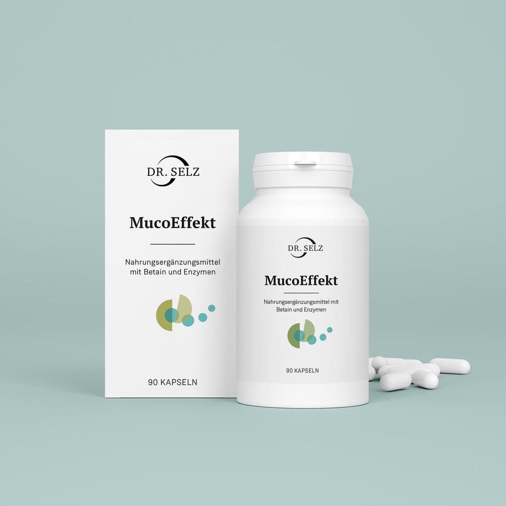 Weiße Kapseln neben einer weißen Flasche und Schachtel. Aufschrift: Dr. Selz MucoEffekt. Nahrungsergänzungsmittel mit Betain und Enzymen.