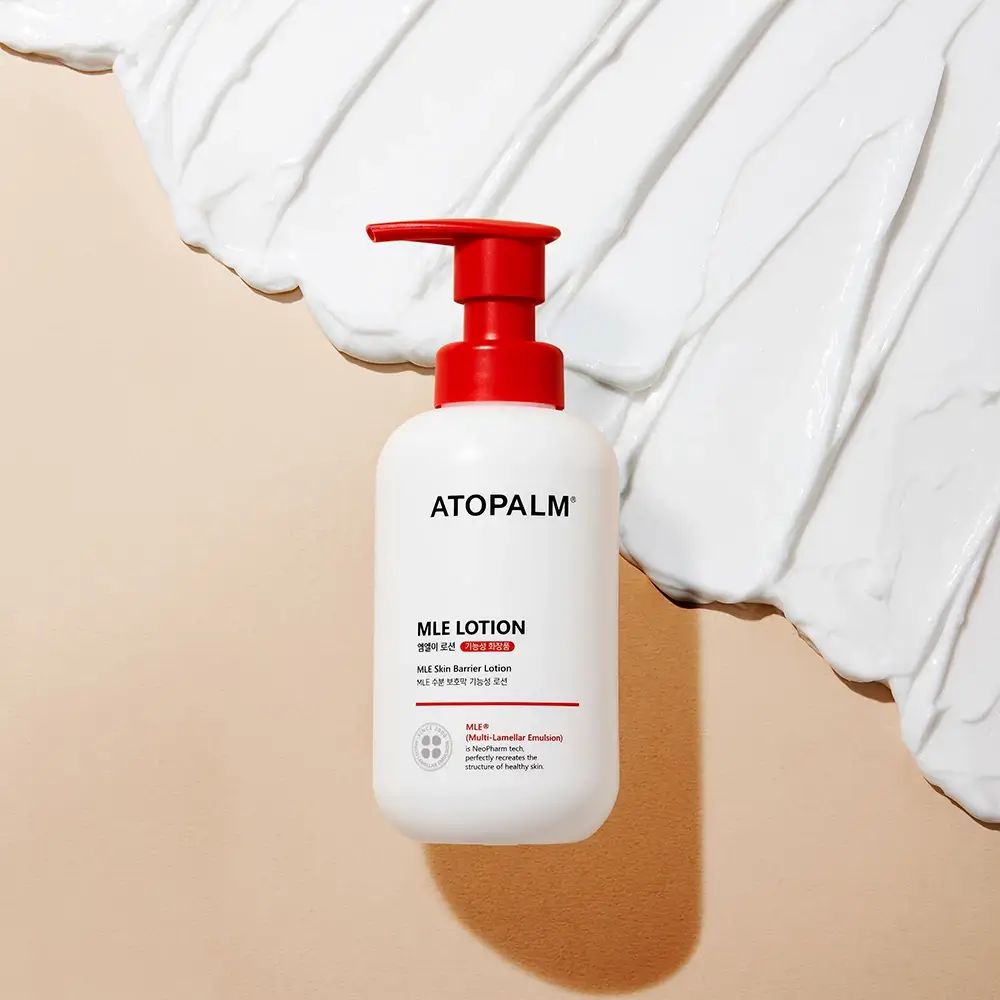 Weiße Flasche mit rotem Pumpkopf. Aufschrift: ATOPALM MLE LOTION. Creme auf Untergrund.