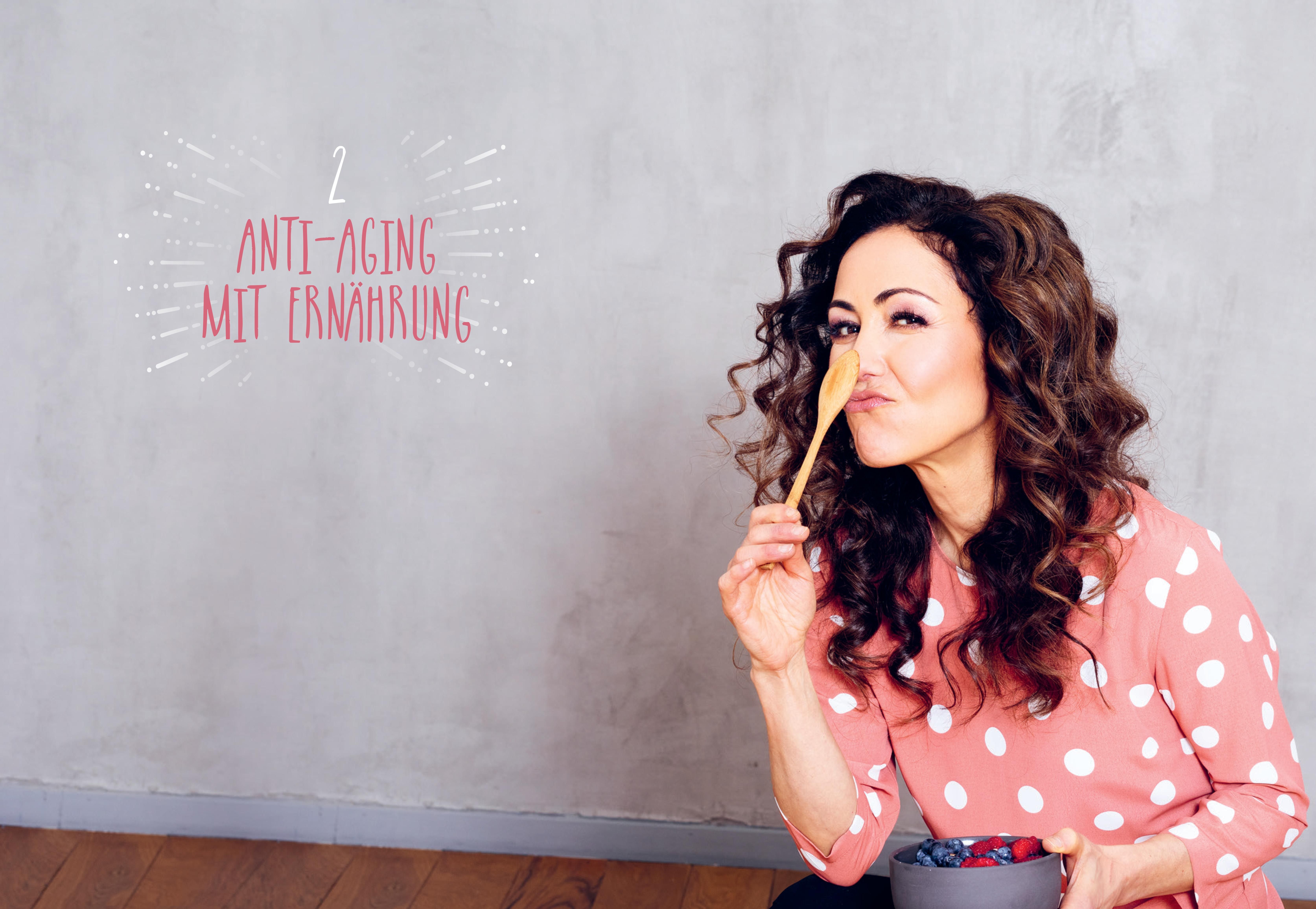 Frau mit Löffel im Mund, hält Schüssel mit Beeren. Text: 2 Anti-Aging mit Ernährung.