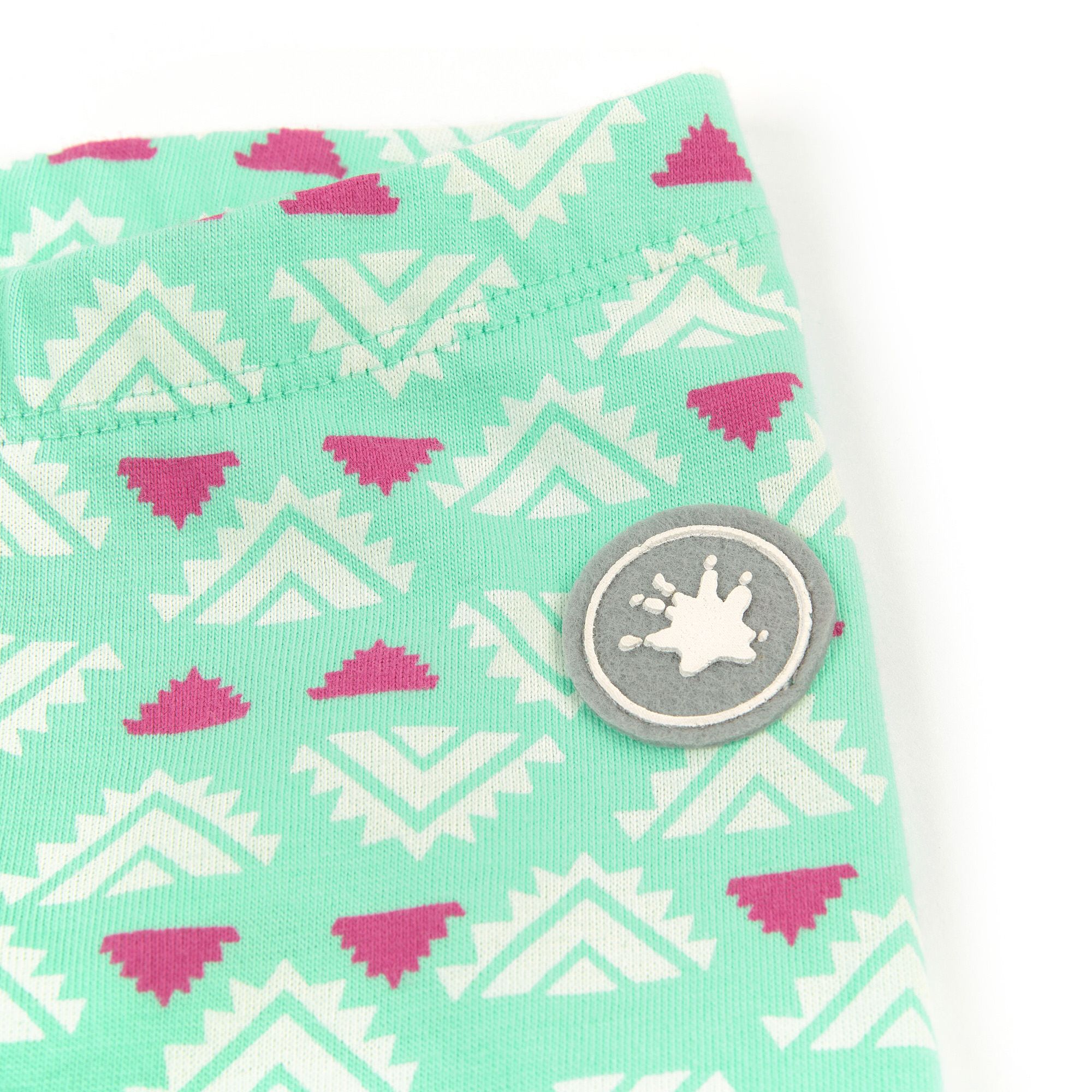 Detailaufnahme des Logos auf einer hellgrünen Baby-Leggings mit weißem und pinkfarbenem Muster.