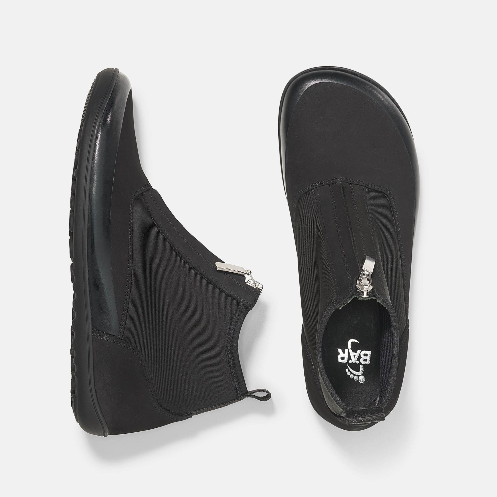 Draufsicht auf zwei schwarze Stiefeletten. Reißverschluss, flache Sohle. Logo auf einer Sohle.
