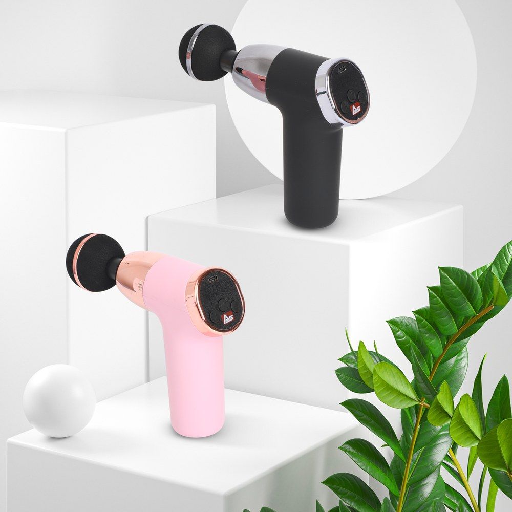 Zwei Massagepistolen, eine rosa und eine schwarze, auf weißen Würfeln.