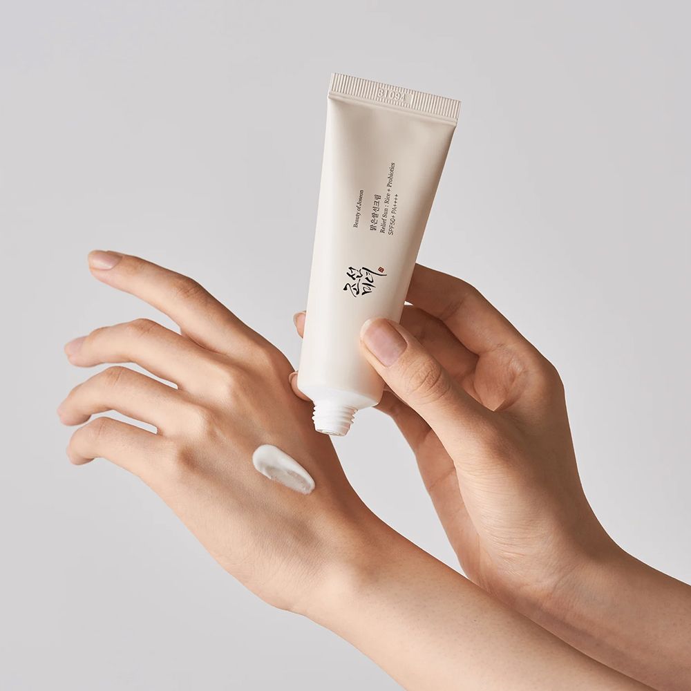 Eine Hand trägt Sonnenschutzmittel aus einer Tube auf die andere Hand auf.