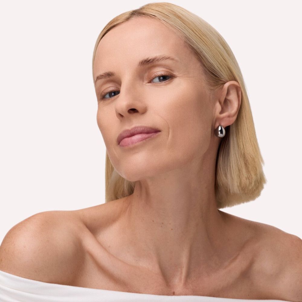 Porträt einer Frau mit blonden Haaren und silbernen Ohrringen. Sie blickt in die Kamera.