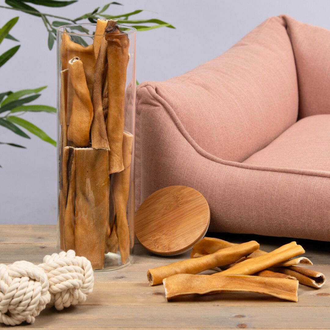 Lyra Pet® Pferdekopfhaut in Glasbehälter und daneben. Braune, längliche Stücke. Holzdeckel und rosa Bett.