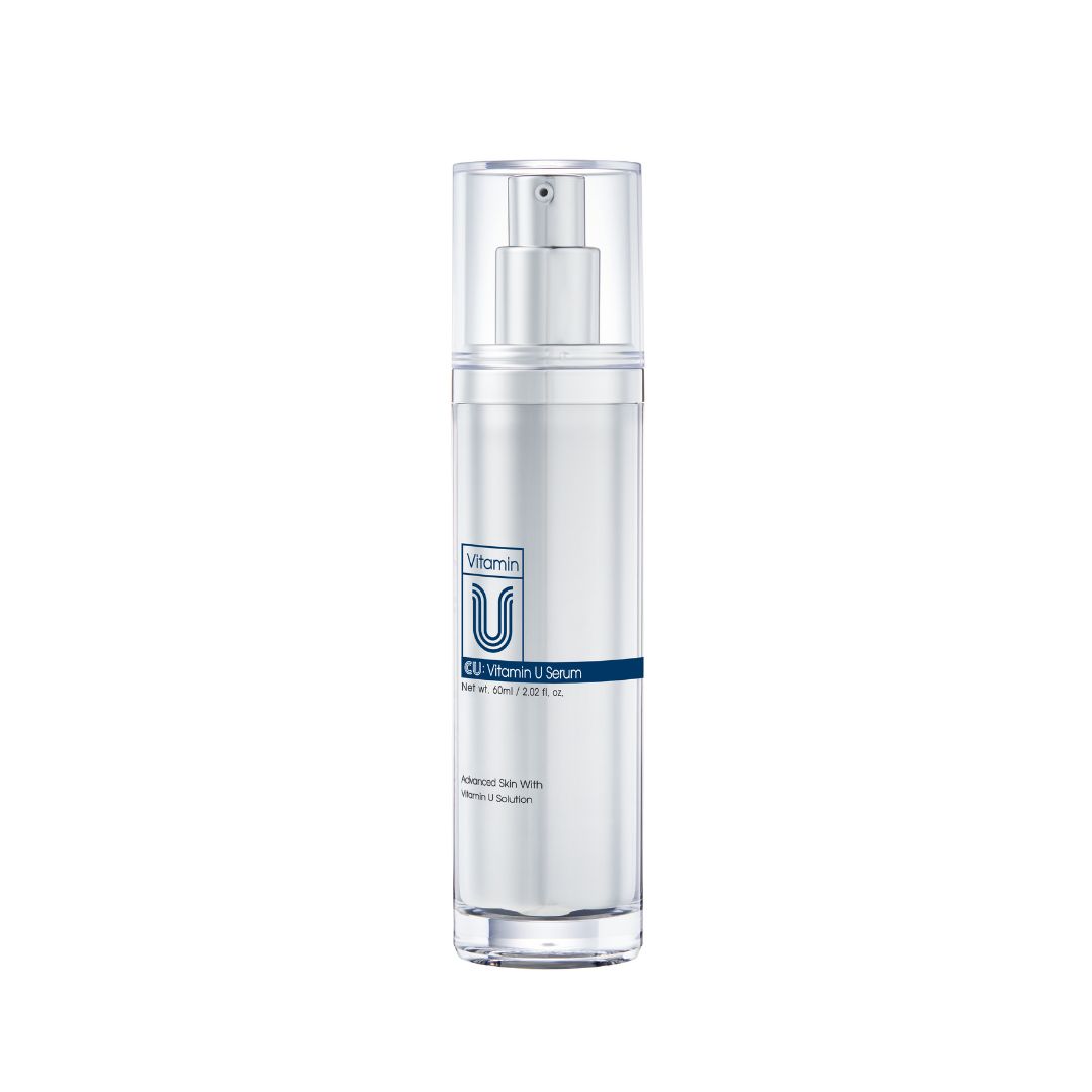 Zylindrische Flasche mit Sprühkopf. Aufschrift: Vitamin U Serum. Blaue horizontale Linie mit Text.