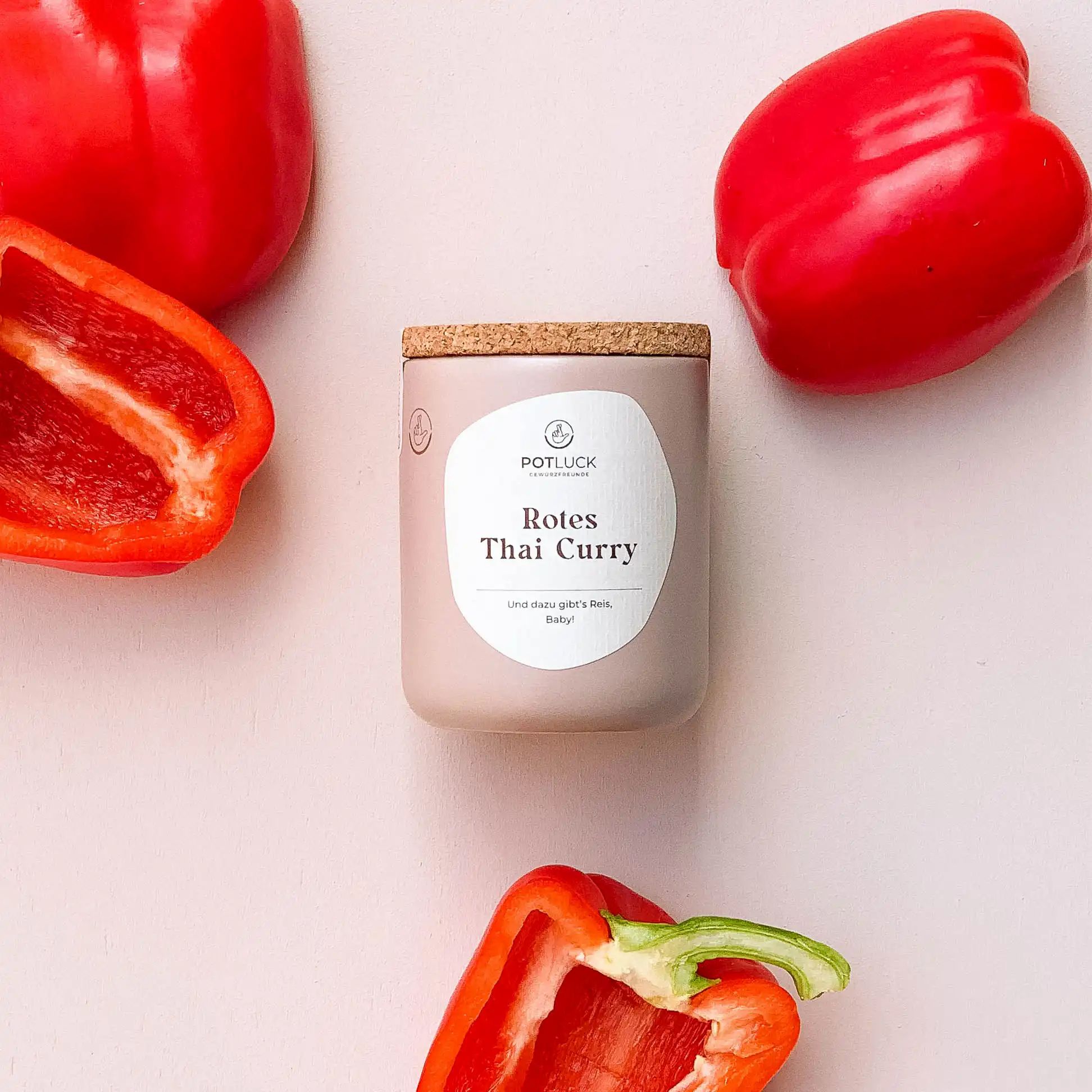 Beige Dose mit Korkdeckel, umgeben von Paprika. Aufkleber "POTLUCK Rotes Thai Curry".