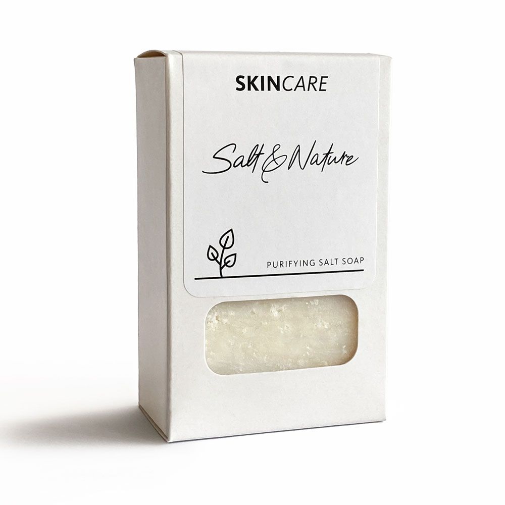 Weiße Verpackung mit Produktnamen und Logo. Sichtfenster zeigt Salzseife. Text: SKINCARE, Salt & Nature, Purifying Salt Soap.