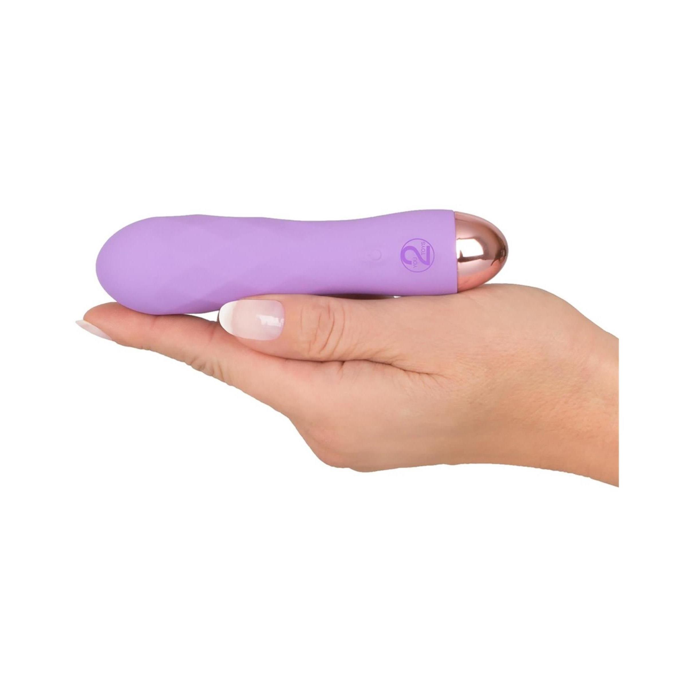 Lila Vibrator in einer Hand gehalten. Goldfarbene Spitze. Power- und Intensitätsanzeige.